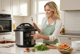 Modelo sorrindo ao lado da panela de pressão elétrica Electrolux PCC20 em uma cozinha moderna e iluminada.