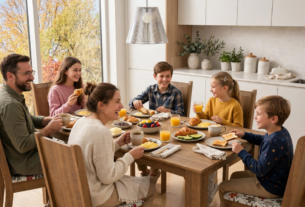 Família reunida ao redor de uma mesa de madeira tomando café da manhã em uma cozinha moderna e iluminada.