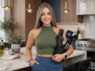 Mulher sorrindo na cozinha moderna segurando um suporte com jogos de silicone de cozinha.